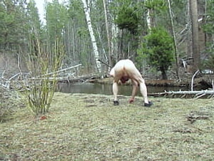 Naked throwing a rock into the creek.